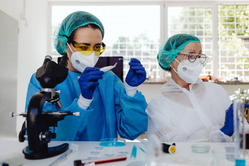 A pair of clinical researching performing tests using a petri dish and microscope