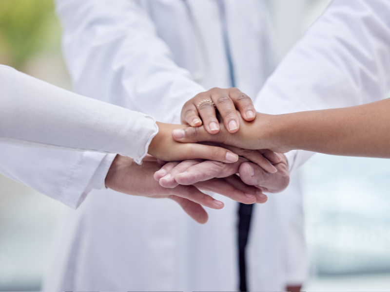 Close-up of the hands of three doctors joined together in collaboration