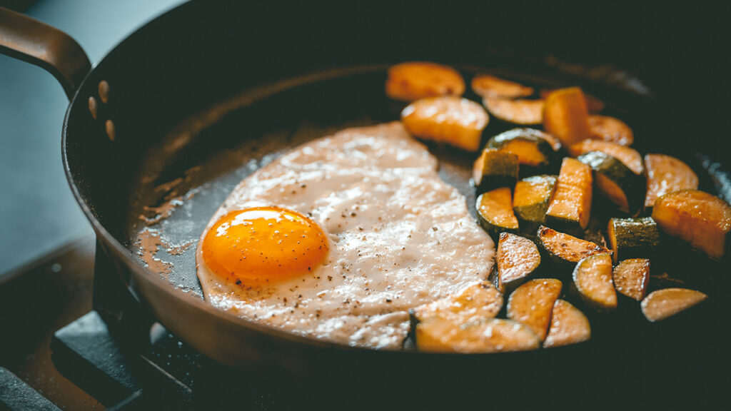 Eggs and vegetables cooking in a non-stick frying pan made with PFAS